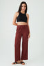Woman wearing a black crop top and maroon wide-leg pants on a white background