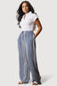 Woman wearing a white polo shirt and blue patterned pants on a white background