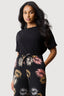 Woman wearing a black jumpsuit with colorful leaf pattern on a white background