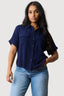 Woman wearing a navy shirt and light blue jeans on a white background