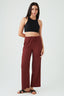 Woman wearing a black crop top and maroon wide-leg pants on a white background