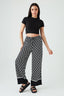 Woman wearing black and white patterned pants with a black top on a white background